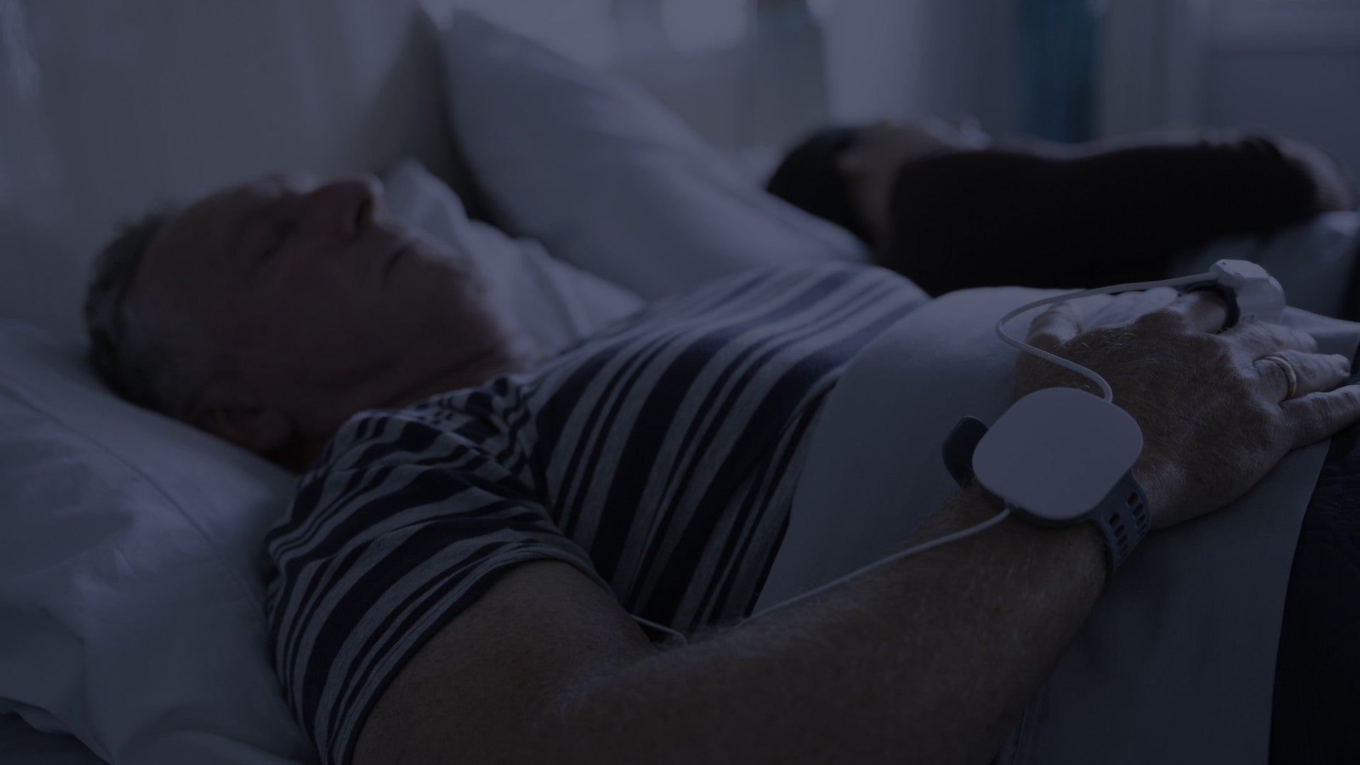 A man sleeping in his own bed wearing the WatchPAT ONE on his wrist