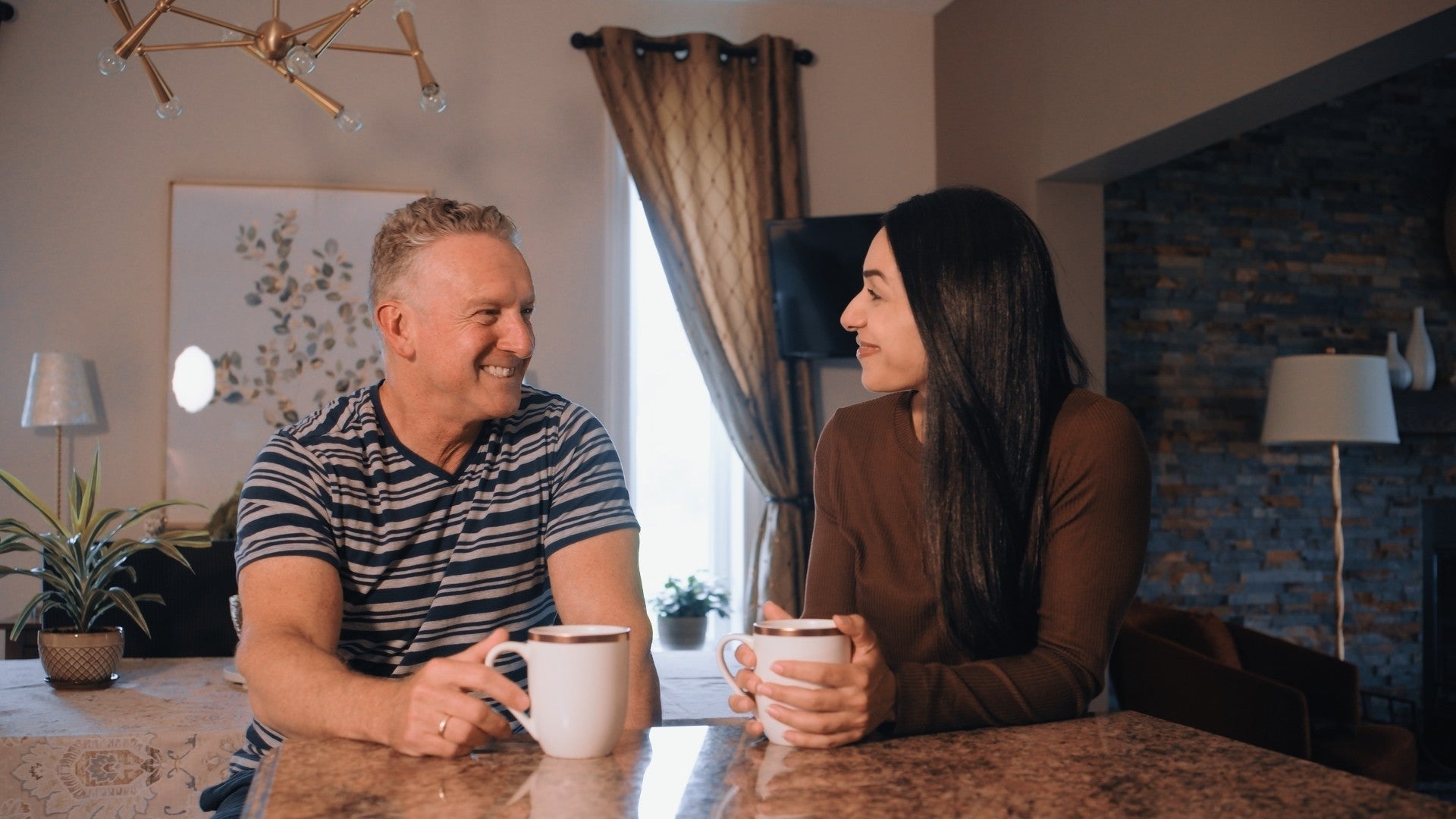 A smiling couple having coffee together in the kitchen the morning after the test